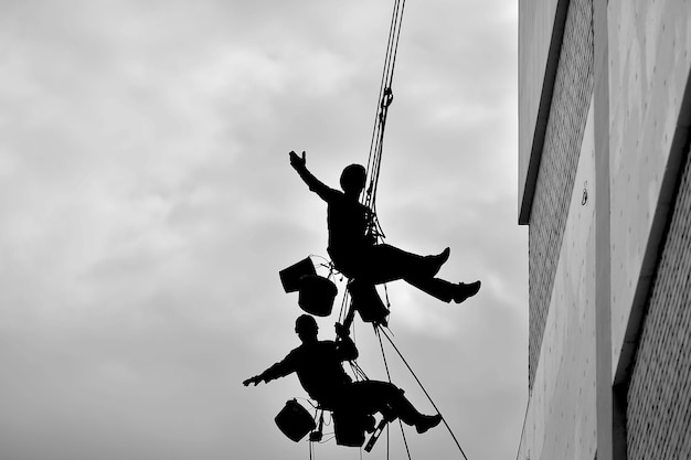 Two professional men insulate a residential building outside. Industrial alpinism. Two climbers insulate the wall of the house on the ropes.