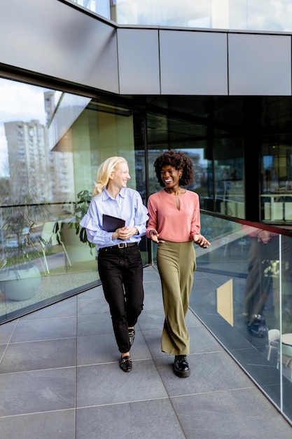 Two Professional Women Sharing a Joyful Conversation at a Modern Office Building