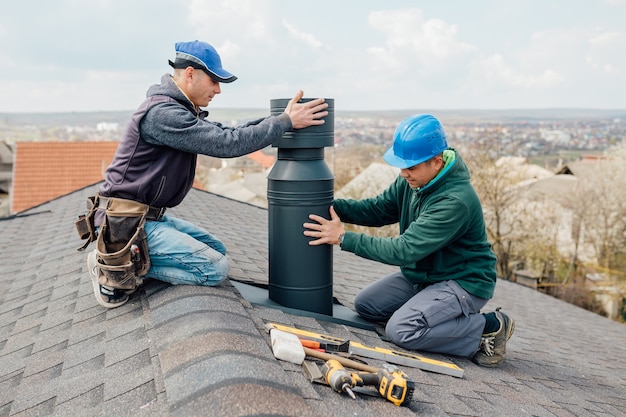 two professional workmens standing roof top and measuring chimney 