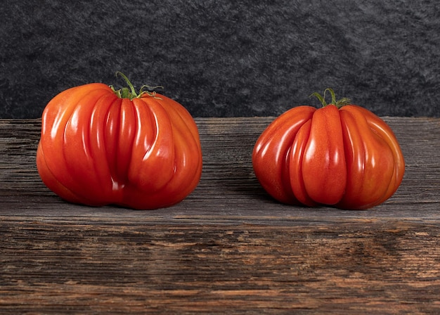 Two Raf Coeur De Boeuf tomatoes on a wooden background