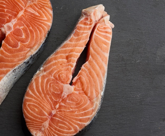 Two raw salmon steaks on a black background