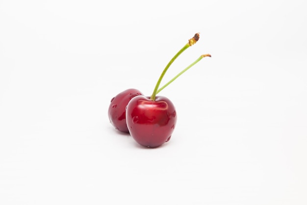 Two red cherries on a white background