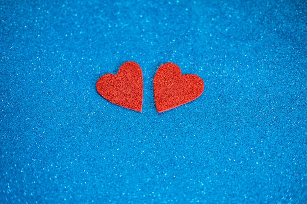 Two red glitter hearts on shiny blue wall