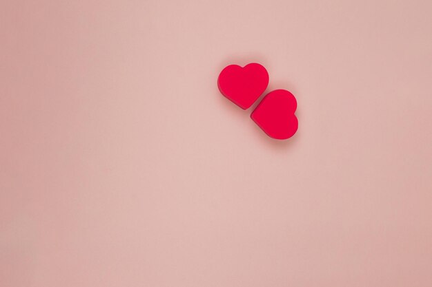 Photo two red hearts on a pink background