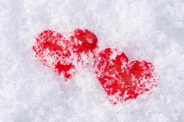 Two red hearts in white snow. Concept of love, relationship, St Valentine's day