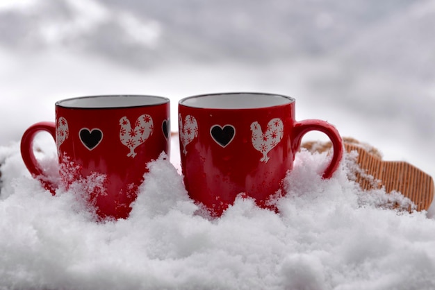 Two red mugs with heart shaped on the snow valentine concept