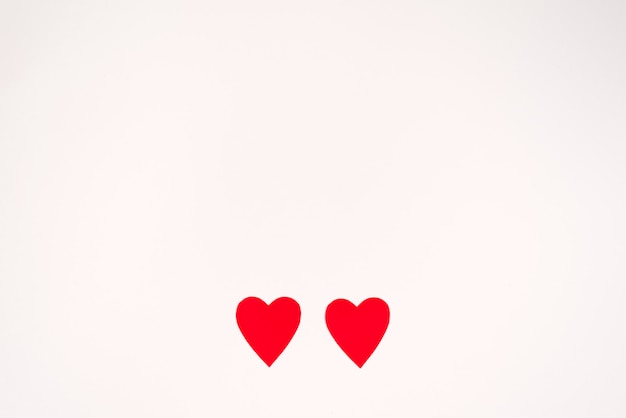 Photo two red paper hearts on a white background, copying space. valentine's day holiday card