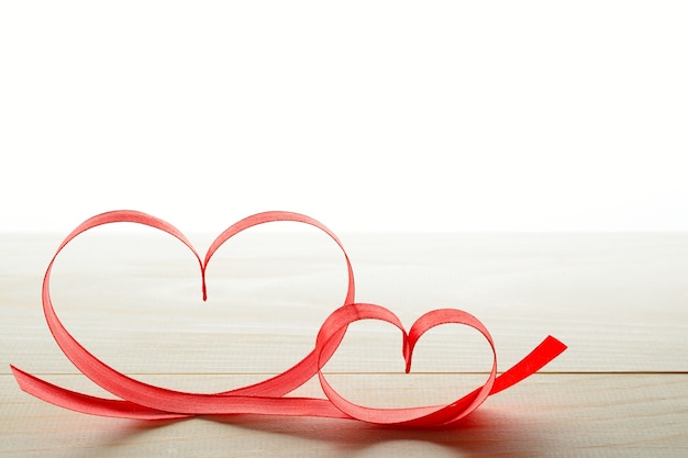 Two red ribbons in heart shape on table