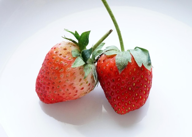 Two red strawberries on white background