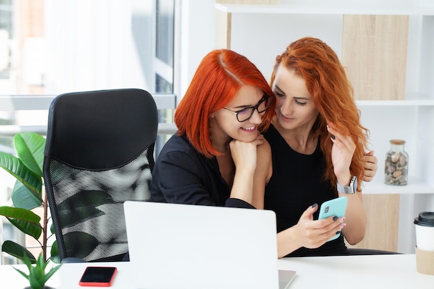 Two redhaired female coworkers trying to solve problem of new project