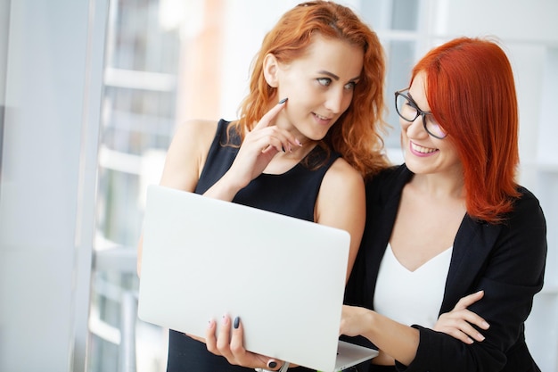 Two redhaired woman work together in the modern office