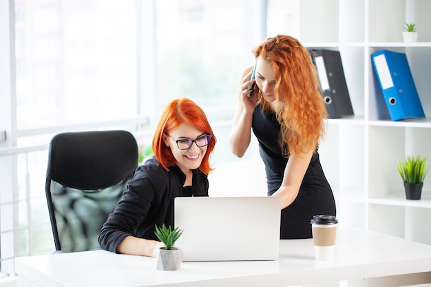 Two redhaired woman work together in the modern office