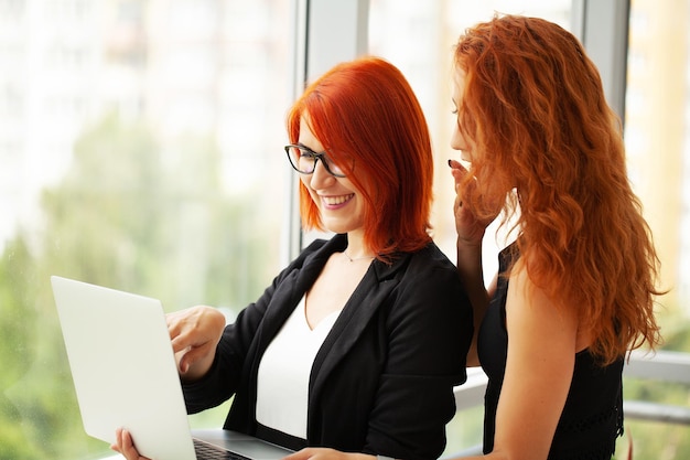 Two redhaired woman work together in the modern office