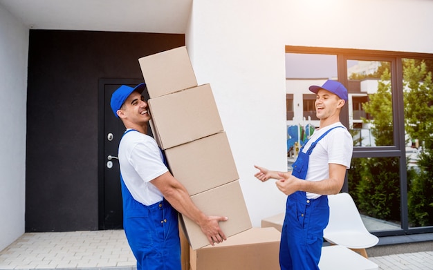 Two removal company workers are loading boxes into a minibus