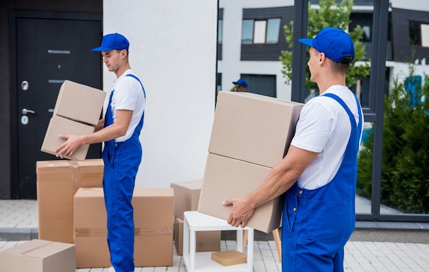 Two removal company workers are loading boxes into a minibus