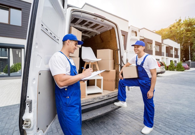 Two removal company workers unloading boxes and furniture from minibus