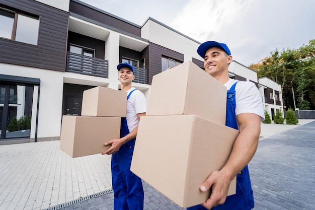 Two removal company workers unloading boxes into new customers home