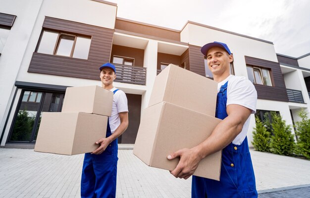 Two removal company workers unloading boxes into new customers home