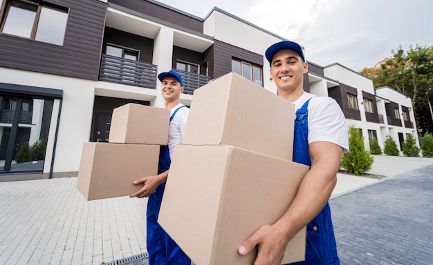 Two removal company workers unloading boxes into new customers home