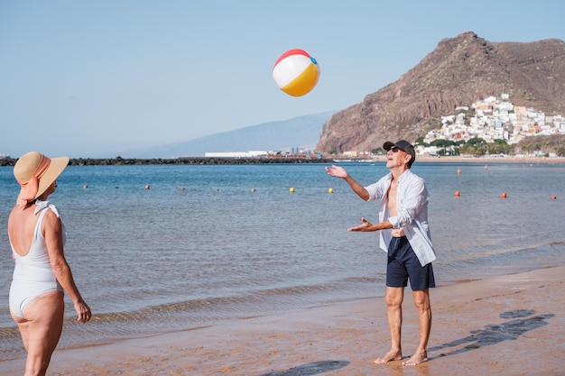 Two retirees playing beach ball during a sunny day and enjoying their retirement Concept lifestyle health care senior sport