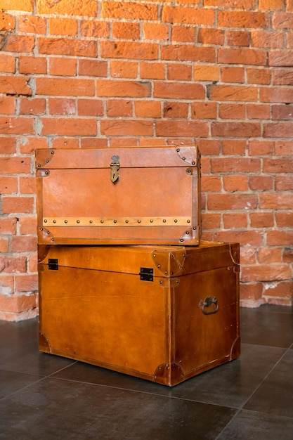 Two retro decorative cases or storage boxes on a brick wall backgroundtwo old trunksantique brown wooden chests with rusty knobs and locks