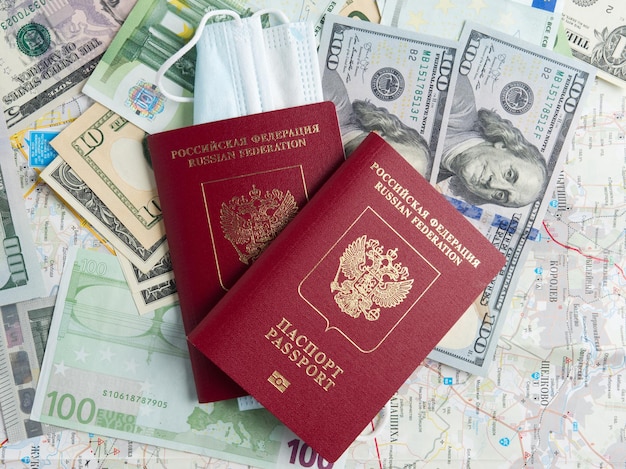 Two Russian passports are on dollar and euro bills A medical mask is attached to one of the passports The concept of traveling during a pandemic and diseases Top view flat lay