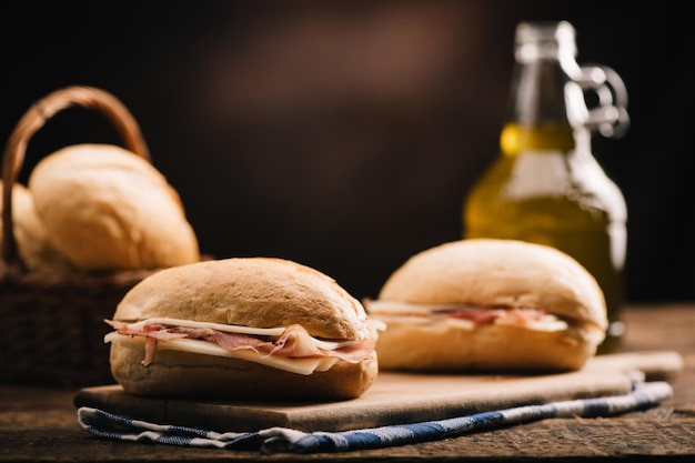 Two sandwiches with ham and cheese on wooden table