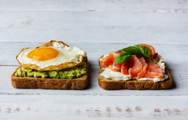 Two sandwiches with smoked salmon cream cheese avocado and fried egg Concept for healthy breakfast