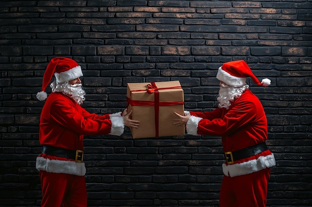 Photo two santa claus with christmas gifts