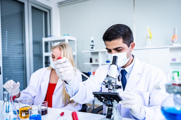 Two scientists are working holding looking at test tube with sample in a chemistry lab scientist or young female and male researcher are doing investigations in Laboratory analysis background