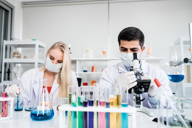 Two scientists are working holding looking at test tube with sample in a chemistry lab scientist