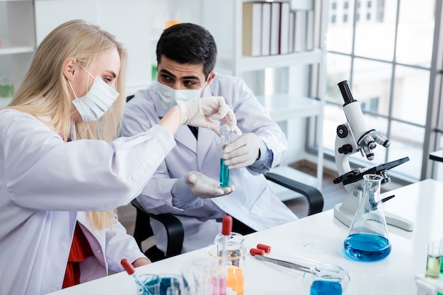 Two scientists are working holding looking at test tube with sample in a chemistry lab scientist