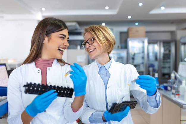 Two scientists are working in laboratory Young female researcher and her senior supervisor are doing investigations with test tubes