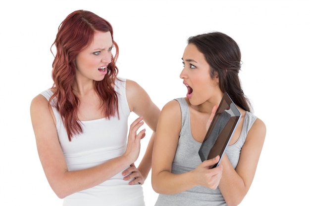 Two shocked young female friends with digital tablet