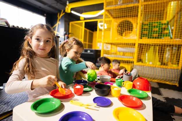 Two sisrers playing in kids kitchen at children play center