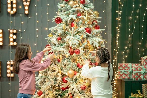 two sisters decorate a christmas tree merry christmas and happy new year concept