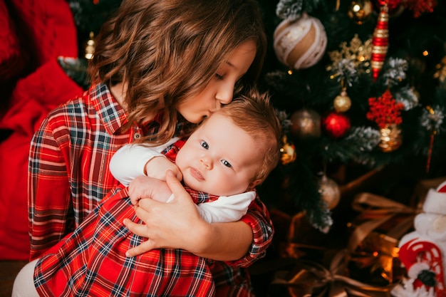 two sisters embrace next to a Christmas tree