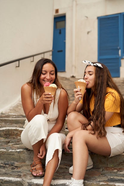 Two sisters having ice cream together outdoors.