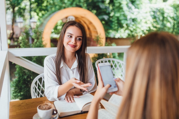 Two sisters learning in the cafe and speaking.