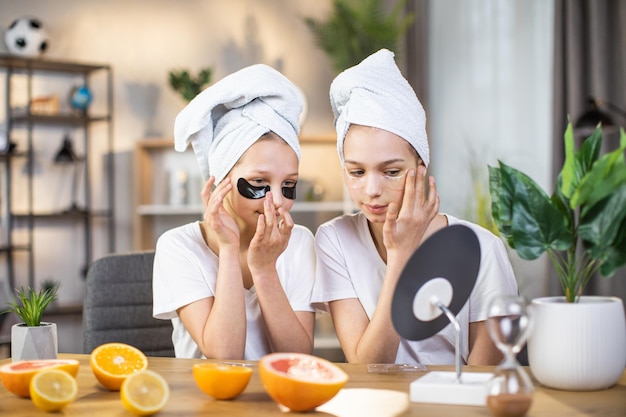 Two sisters taking care of skin under eyes with patches