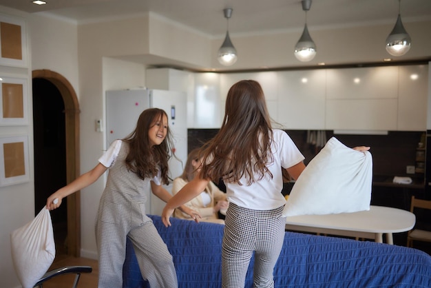 Two sisters wearing white pajamas fight with pillows and have fun concept of youth wellness and heal