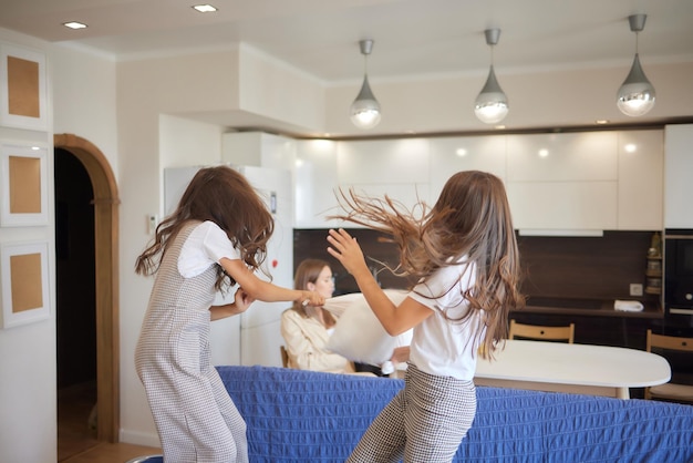 Two sisters wearing white pajamas fight with pillows and have fun Concept of youth wellness and health happiness and freedom