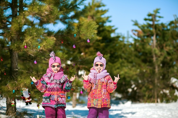 Two sisters in winter in a snowy forest playing in the snow