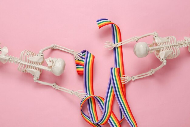 Two skeletons and rainbow ribbon on a pink background Homosexual relationship Creative layout