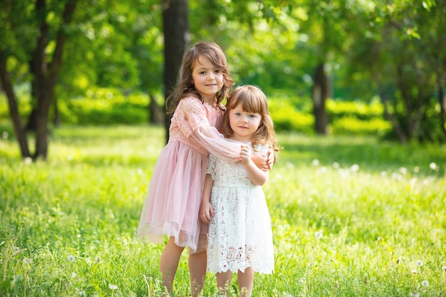 Two small beautiful girls children together happy play and laugh in nature