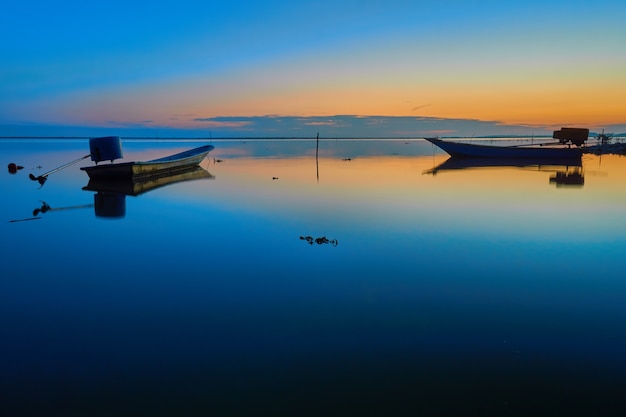 Two small boat on the water at sunrise with reflection.