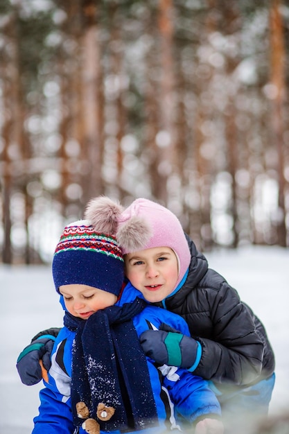 Two small children with sleds in the forest Family walk in the woods