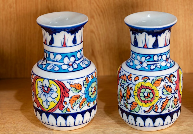 Photo two small vases with a floral design on them sit on a shelf.