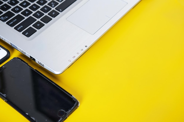 Two smartphones beside a laptop isolated on yellow background