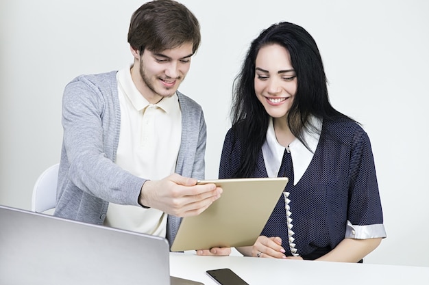 Two smiling casual designers working with laptop and tablet in the office. Man  wooman teamwork.